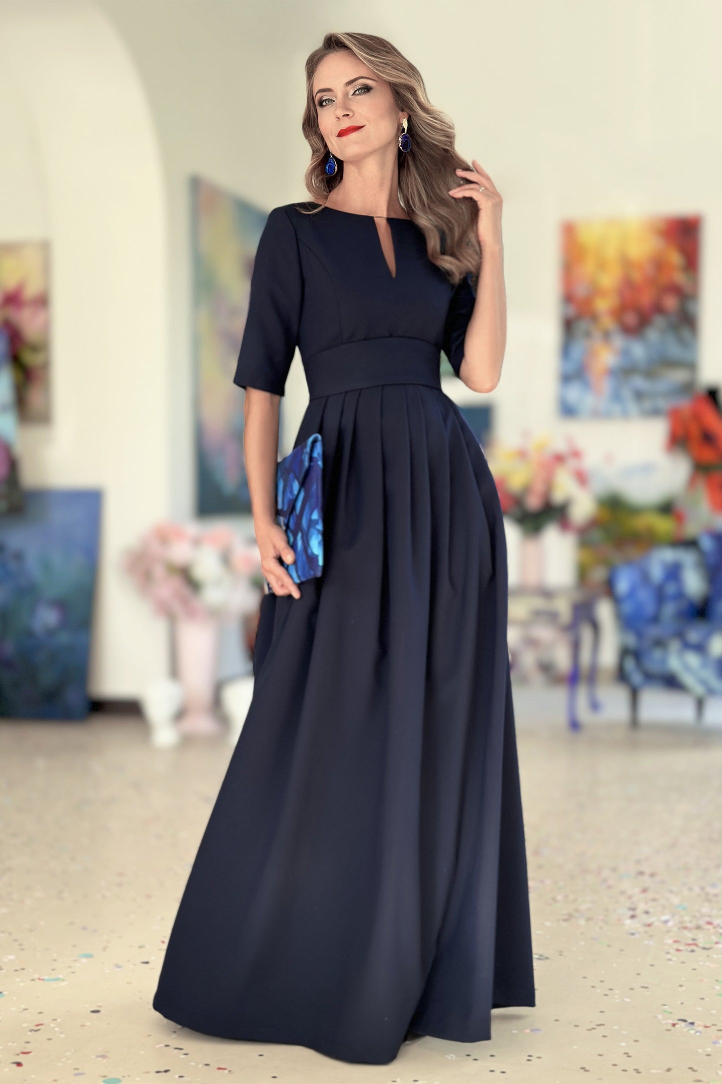 Long dark blue dress with pleats. Golden color detail in neckline